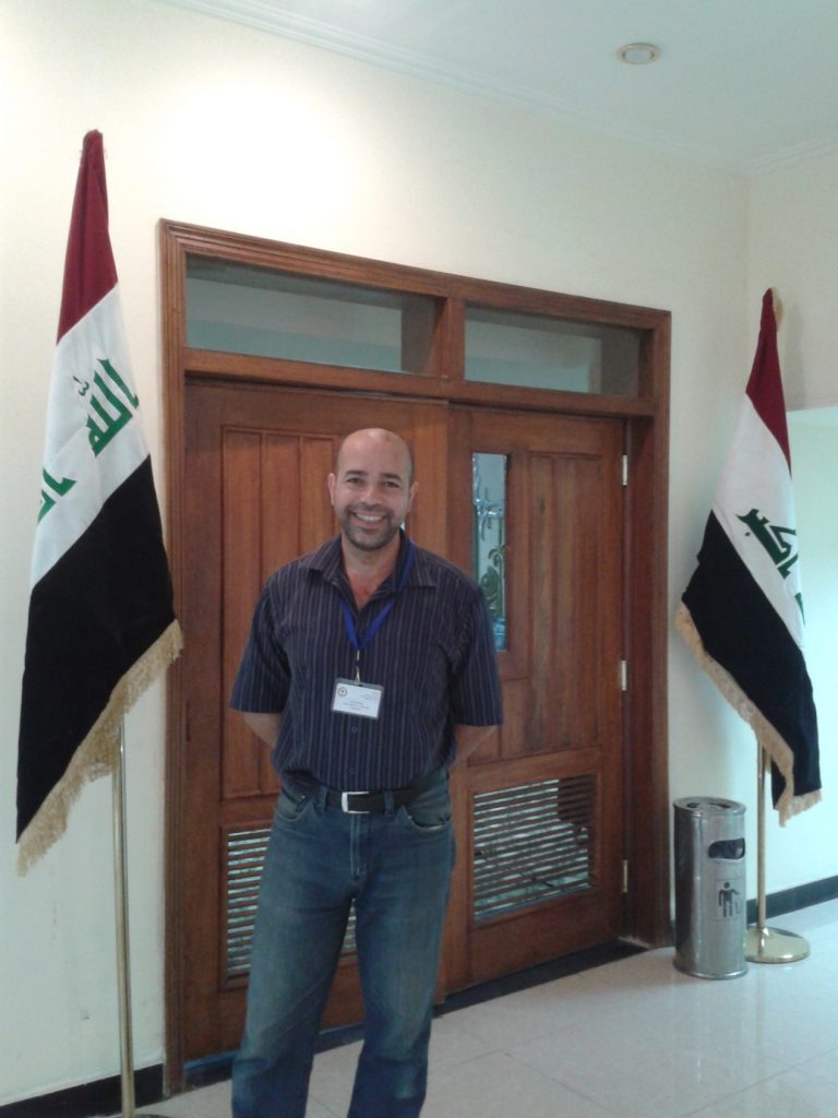writer indoors in front of a door and flags